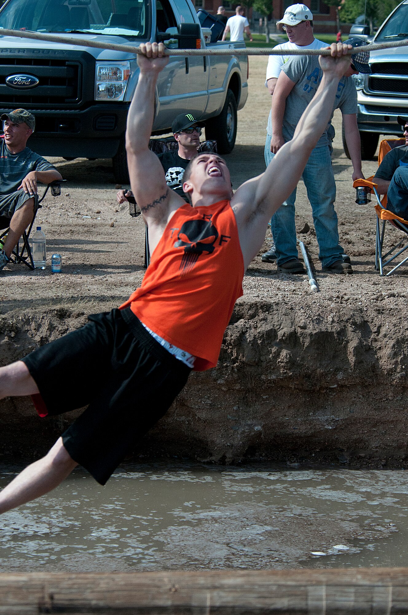 Staff Sgt. Joshua Howard, 90th Security Support Squadron, works his way, hand-over-hand, along a rope stretched over a muddy pit of water as he competes in the Canyon Death Walk during last year’s Frontiercade event Aug. 24, 2012. Frontiercade is a base-wide event billed as a “sports day,” which gives Airmen a chance to foster teamwork and increase esprit de corps throughout the wing. This year’s Frontiercade is Aug 21. (U.S. Air Force photo by R.J. Oriez)