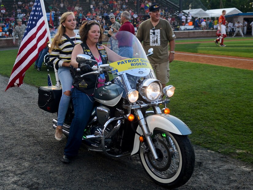 Kenzie McDougall, a Gold Star family member, rides passenger with a Patriot Guard Rider, Aug. 3, 2013, in Hampton, Va. Fort Eustis, Va., Survivor Outreach Services regularly hosts events for families who have lost a loved Service member, giving them an opportunity to share their stories or enjoy the company of other survivors. (U.S. Air Force photo by Airman 1st Class Austin Harvill/Released)