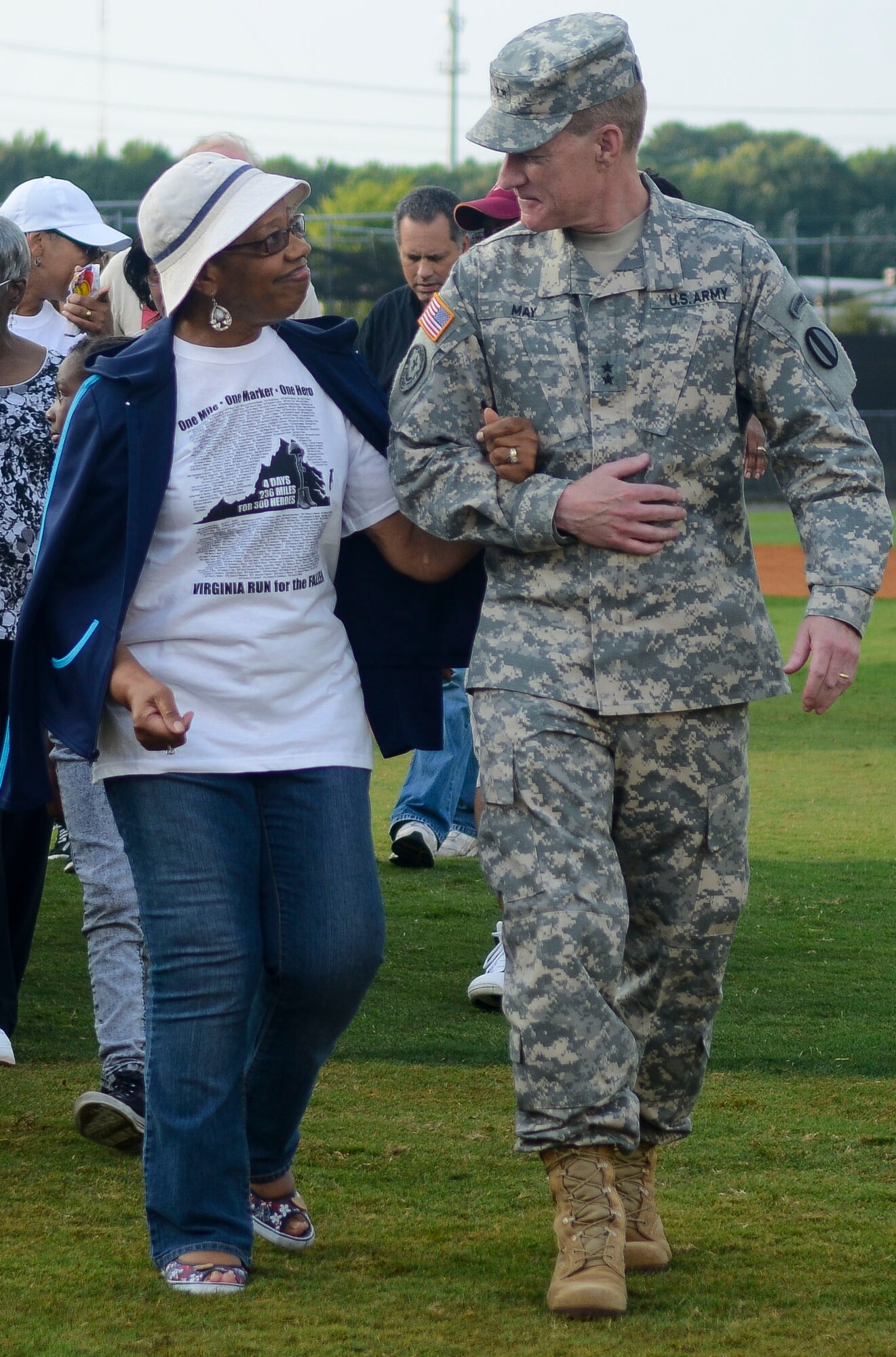 U.S. Army Maj. Gen. Bradley May, Training and Doctrine Command Initial Military Training Center of Excellence deputy commander, escorts Erline Wimberly, a Gold Star family member, off a baseball field, Aug. 3, 2013, in Hampton, Va. Fort Eustis, Va., Survivor Outreach Services assists families of fallen Service members coping with their loss by introducing them into a community of individuals who have endured the same hardships. (U.S. Air Force photo by Airman 1st Class Austin Harvill/Released)