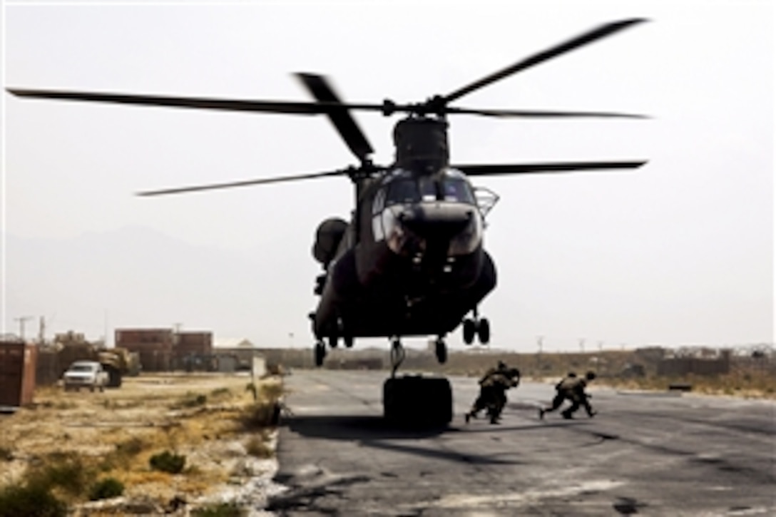 U.S. soldiers rush off the flightline after slingloading two 500-gallon fuel blivets under a CH-47 Chinook helicopter on Bagram Airfield, Afghanistan, July 30, 2013.