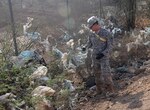 A Soldier from Task Force Longrifles pulls plastic bags from bushes by Camp Lemonnier, Djibouti, on Dec. 12, 2012.