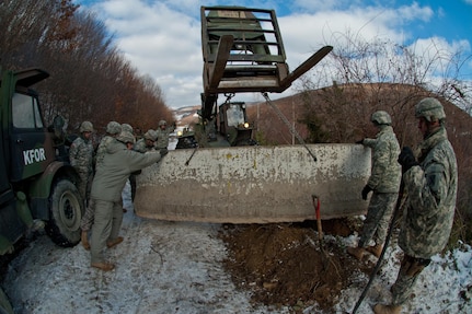 Kosovo Force soldiers from Multinational Battle Group-East maneuver a concrete barrier into position in Zubin Potok, Kosovo, on Jan. 8, 2013.