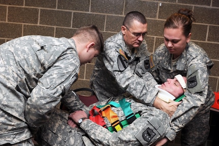 Combat medic students place a "patient" on a backboard after assessing and stabilizing him following a simulated vehicle crash.