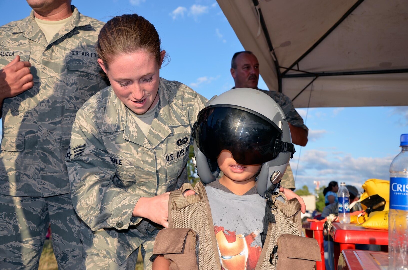 Senior Airman Beverly Cole, with the New Hampsire Air National Guard's 157th Air Refueling Wing, assists a Salvadoran child with wearing an aircrew flight helmet and vest at the 2013 Ilopango Air Show in Ilopango, El Salvador as part of the State Partnership Program, Jan. 26. The New Hampshire National Guard has partnered with El Salvador as part of the SPP since 2000 and has taken part in numerous yearly subject matter expert exchanges.