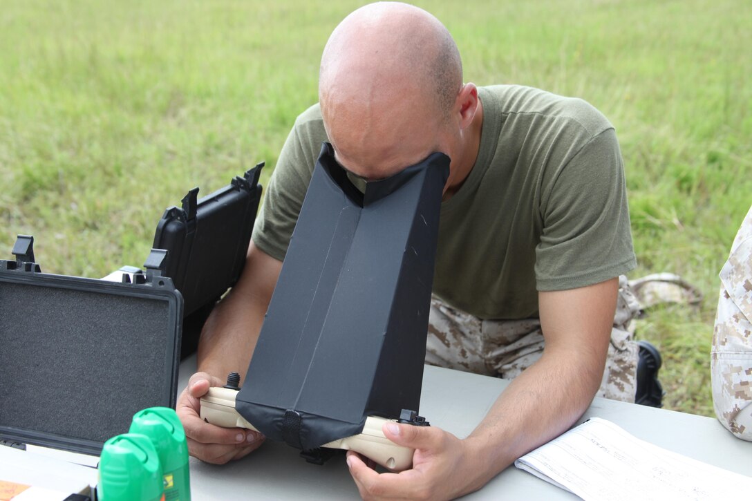 Lance Cpl. Justice C. Thomas, an intelligence analyst with 1st Battalion, 6th Marine Regiment, looks into a controller hood, allowing him to view the screen located on the controller of the Unmanned Aircraft System as he holds it during the Raven Operators Course at Landing Zone Woodpecker Aug 2.
