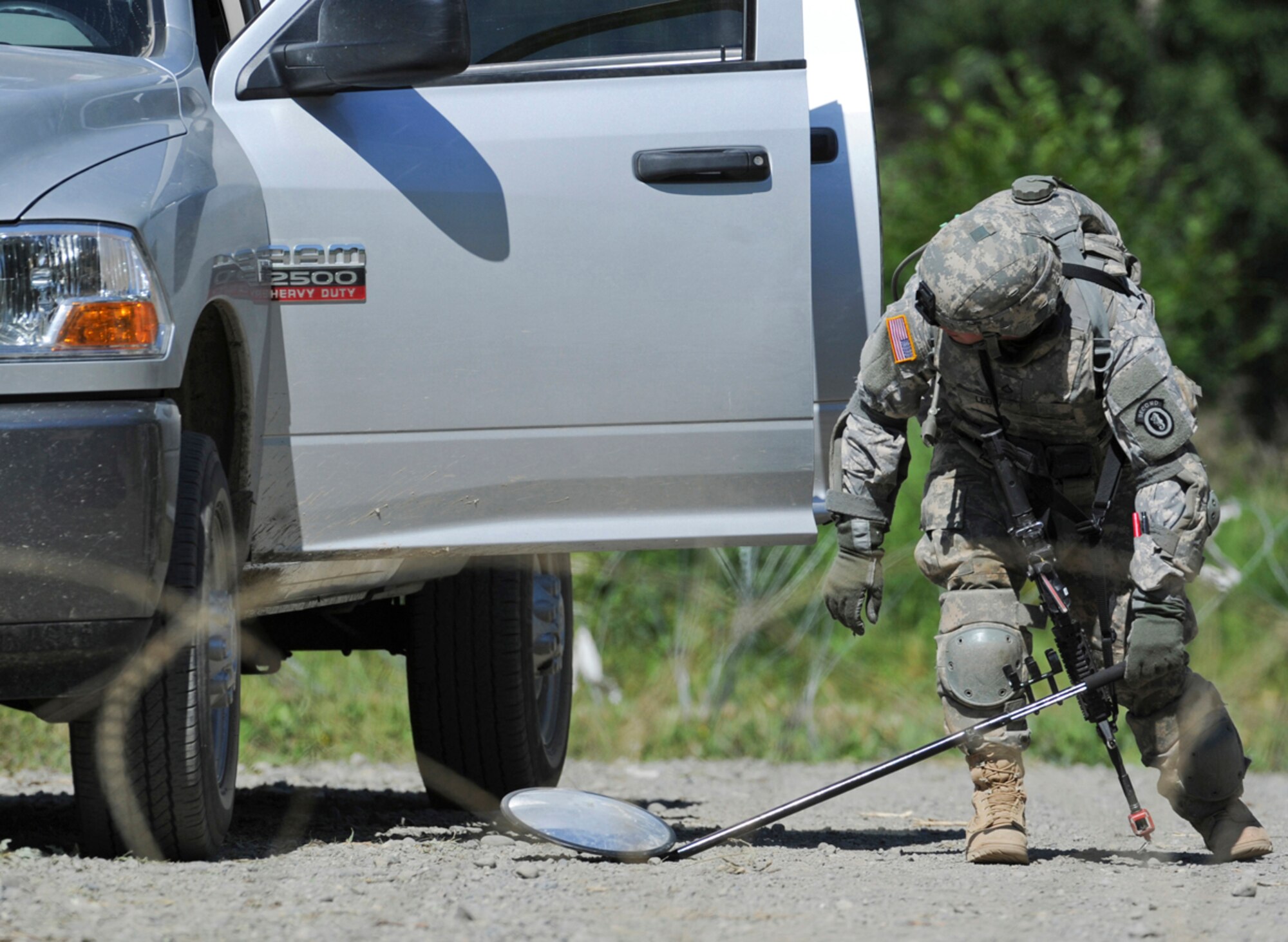 JOINT BASE ELMENDORF-RICHARDSON, Alaska -- Army Pfc. Eric Leow, a native of Laingsburg, Mich., assigned to the 164th Military Police Company, 2d Engineer Brigade, searches the under side of a vehicle at a check point in a situational training exercise lane during team qualifications at Joint Base Elmendorf-Richardson, Wednesday, July 24, 2013.  The military police Soldiers trained on various team-based scenarios aimed at testing their abilities to adapt to rapidly changing situations under stressful physical and mental conditions.   (U.S. Air Force photo/Justin Connaher)