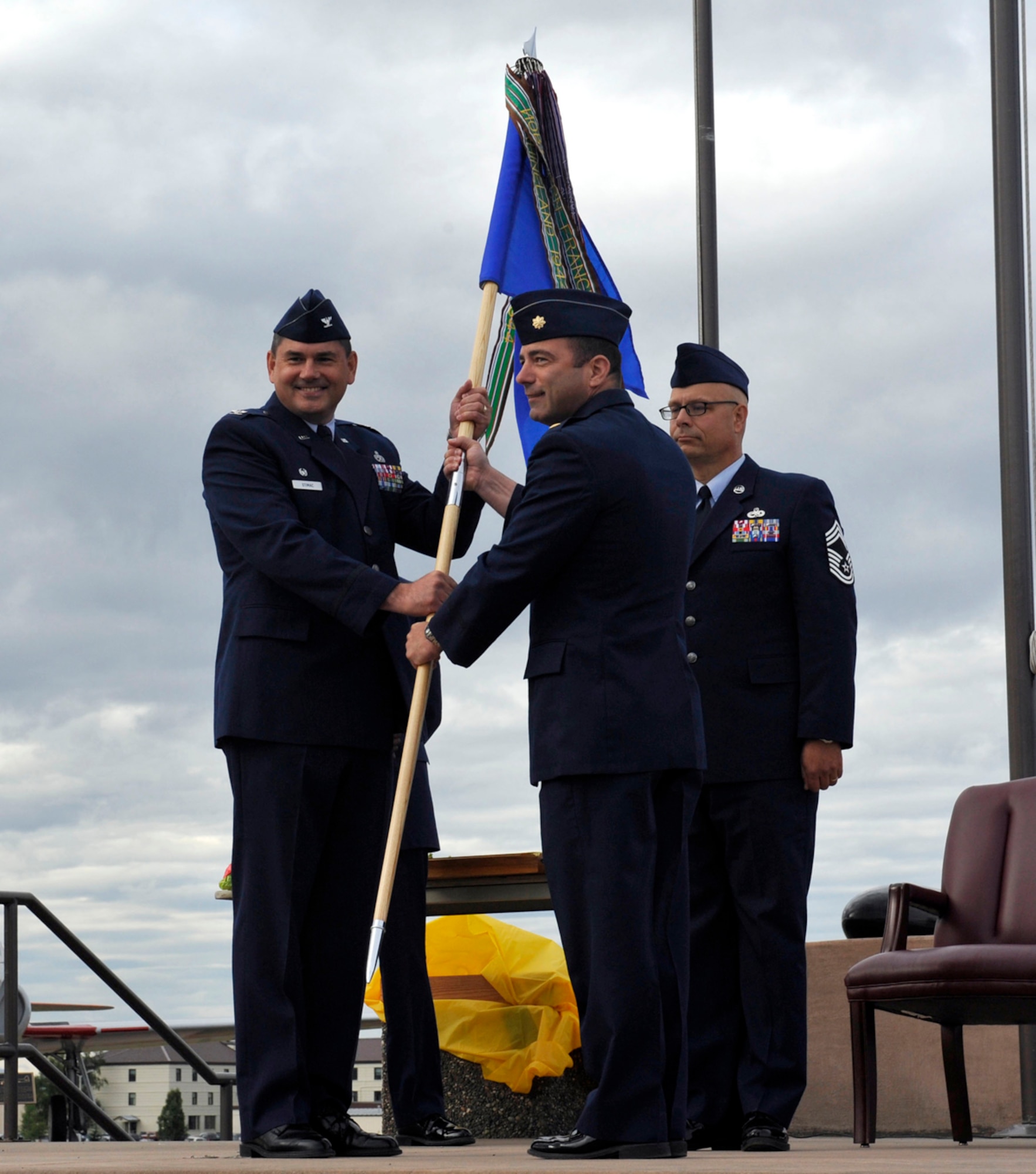 Air Force Col. David Stimac, 3rd Maintenance Group commander (left), receives the 3rd MOS flag from former 3rd Maintenance Operations Squadron commander Air Force Maj. Joseph Schmidt at Heritage Park.  Both commanders rolled the squadron flag during the inactivation ceremony of the 3rd Maintenance Operations Squadron Aug. 5, 2013. The ceremony was hosted to commemorate the 3rd MOS and its redefinition as the 3rd Maintenance Operations Flight. (U.S. Air Force photo/Airman 1st Class Tammie Ramsouer)
