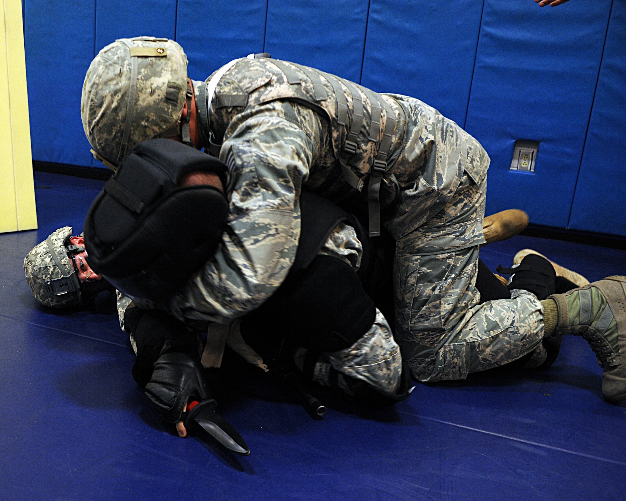 Participants in the U.S. Army Basic Combatives Course wrestle a combative to the ground during a scenario at Davis-Monthan Air Force Base, Ariz., July 25, 2013. The course teaches armed forces members basic hand-to-hand combat to be used to subdue combatants in close-quarter engagements. The course is currently only opened to active duty, Reserve, Guard and retired military personnel. (U.S. Air Force photo by Senior Airman Timothy Moore/Released)