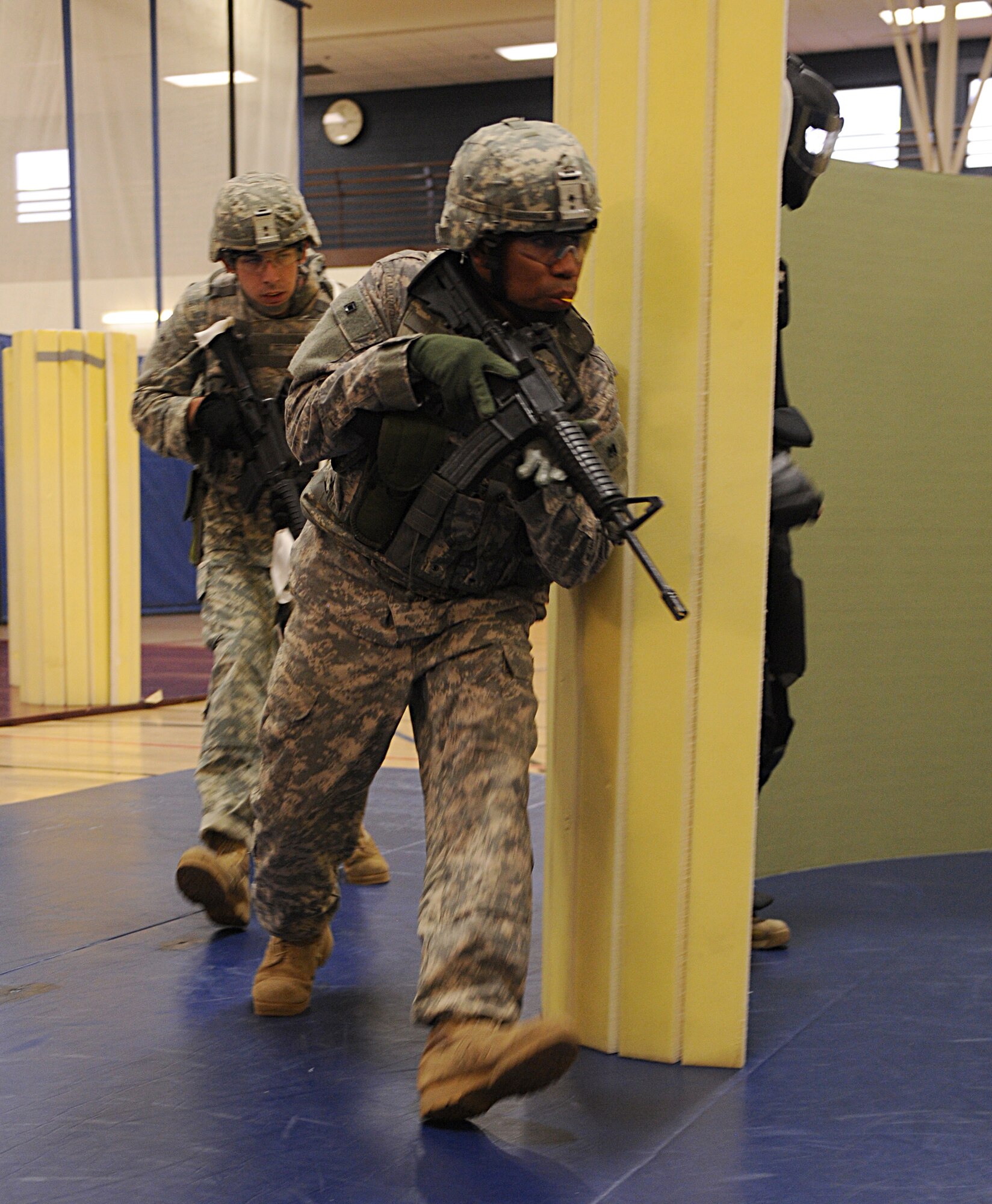 U.S. Army soldiers from the 1st Battlefield Coordination Detachment move around a barrier during a scenario of the U.S. Army Basic Combatives Course at Davis-Monthan Air Force Base, Ariz., July 25, 2013. Participants were tasked to go into the area, recognize and subdue combatants using non-lethal tactics they learned in the course. (U.S. Air Force photo by Senior Airman Timothy Moore/Released)