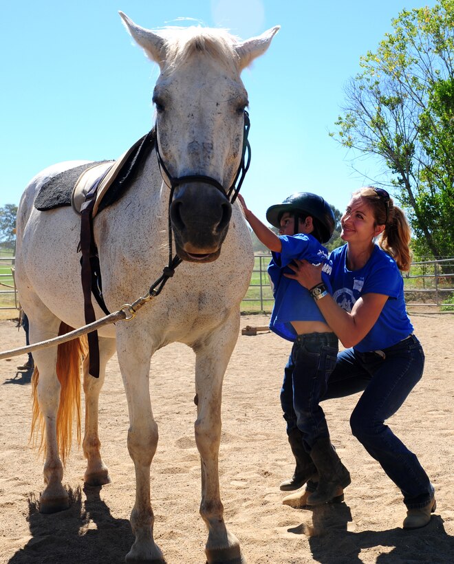 Maj. Michelle, 427th Reconnaissance Squadron, lifts James Rojas onto a horse at Batti Ranch in Lincoln, Calif., on Aug. 2, 2013. Beale youth’s attended the ranch to gain experience and learn about horses. (U.S. Air Force photo by Airman 1st Class Bobby Cummings/Released)