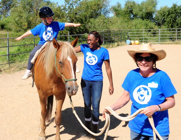 Madyson Mahaney goes no-hands while on a horse ride at Batti Ranch in Lincoln, Calif., on Aug. 2, 2013. Madyson is escorted by Airman 1st Class Equasha (center), 48th Intelligence Squadron, who volunteered to help during the horse camp. (U.S. Air Force photo by Airman 1st Class Bobby Cummings/Released)