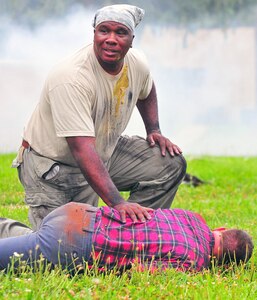Sgt. Curtis Brown (kneeling) calls for help for Sgt. William Pedigo, who simulates being injured during the Vibrant Response 13-2 exercise at the Muscatatuck Urban Training Complex near Butlerville, Ind., July 31. Brown and Pedigo serve with the Maintenance Technician Company, Missouri National Guard. (Photo by Sgt. Will Hill)