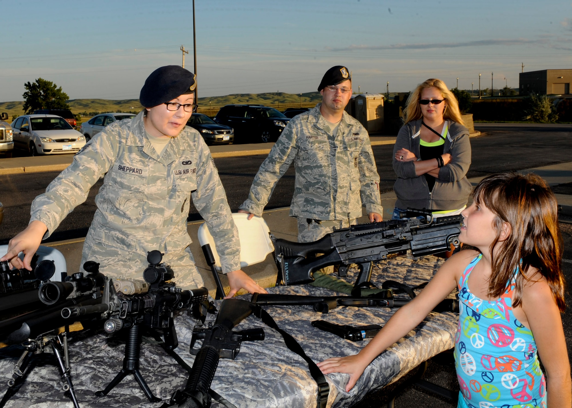 Staff Sgt. Elizabeth Sheppard, 28th Security Forces Squadron combat arms instructor, explains a weapons display to 7 year-old Evelynn Joyce, daughter of Master Sgt. Tonya Joyce, 28th Medical Operations Squadron mental health flight chief, during the National Night Out event at Douglas High School in Box Elder, S.D., Aug. 7, 2013. The event provided an opportunity for both the local community and Ellsworth Airmen to interact with one another and helped to strengthen community ties. (U.S. Air Force photo by Airman 1st Class Anania Tekurio/Released)