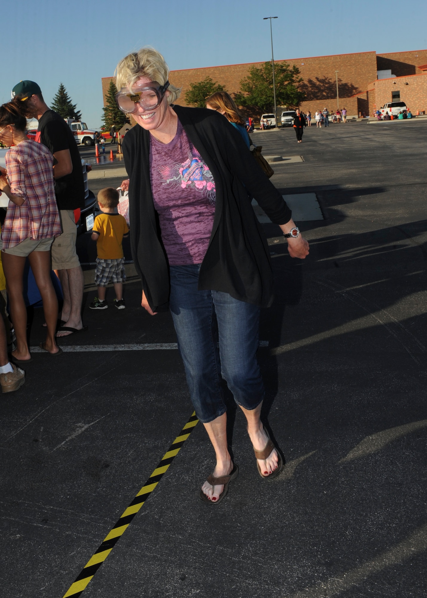 Col. Susan Pietrykowski, 28th Medical Group commander, walks the sobriety check line while wearing impairment goggles that simulate the effects of alcohol during the National Night Out event at Douglas High School in Box Elder, S.D., Aug. 7, 2013. The 28th Medical Operations Squadron Alcohol, Drug and Prevention Treatment information booth provided visitors with the opportunity to learn about the dangers of alcohol and to experience the effects alcohol has on an individual when consumed at high levels through various activities. (U.S. Air Force photo by Airman 1st Class Anania Tekurio/Released)