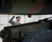 KUNSAN AIR BASE, Republic of Korea --  Army Spc. Zoë Trinca, Alpha Battery 2nd Battalion, 1st Air Defense Artillery Regiment patriot launching station enhanced operator and maintainer, gives a signal while observing Patriot missile launching station movement during a training drill July 25, 2013. Trinca and the rest of Alpha Battery conducted the drill as part of a battalion field training exercise. (U.S. Air Force photo by Senior Airman Clayton Lenhardt/Released)
