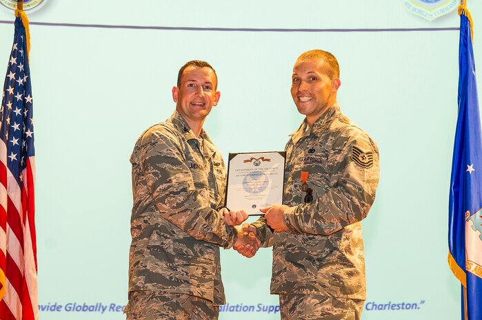Col. Michael Mongold, 628th Mission Support Group commander, presents Tech. Sgt. Hartley, 628th Security Forces Squadron dog handler, with the Air Force Combat Action medal certificate July 24, 2013, at Joint Base Charleston - Air Base, S.C. (U.S. Air Force photo/ Senior Airman George Goslin)
