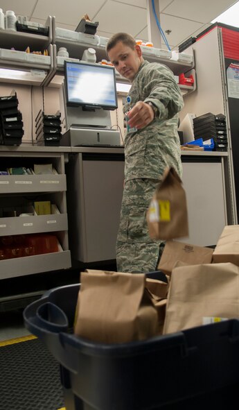 U.S. Air Force Capt. James Pierce, 23d Medical Group pharmacist, tosses a refill into a pile of prescriptions to be dispatched to the Moody Base Exchange pharmacy at Moody Air Force Base, Ga., Aug. 5, 2013. Pharmacy technicians and pharmacists verify the name, date of birth and labels are all correct before dispatching medications. (U.S. Air Force photo by Airman 1st Class Sandra Marrero/released)
