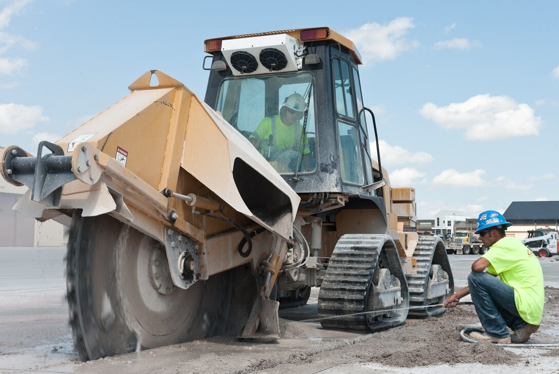 Jack Blakeman and Preston Hansen, Complete Contracting Solutions employees, use a trencher to cut through concrete during deconstruction of row 70 on the flightline at Ellsworth Air Force Base, S.D., Aug. 5, 2013. The construction teams are renovating 22 aircraft parking spots as part of a 6-month project to refurbish the flightline. (U.S. Air Force photo by Airman 1st Class Alystria Maurer/Released)