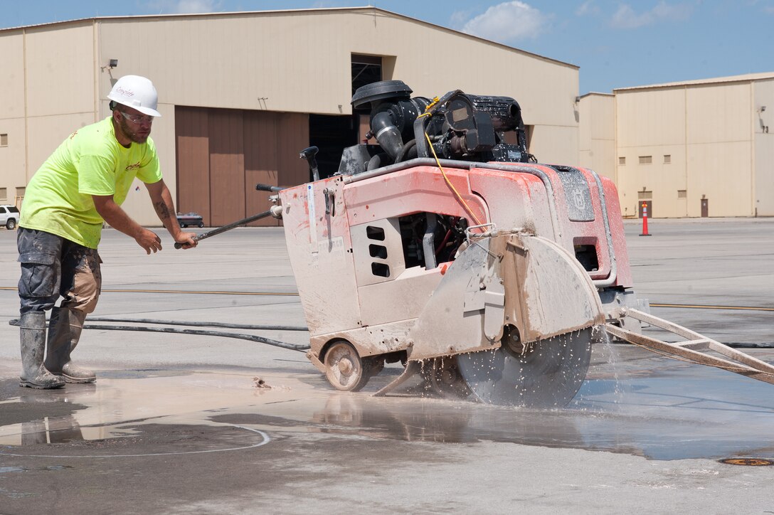 Zach Danielson, Complete Contracting Solutions employee, uses a saw to cut through concrete during deconstruction of row 70 on the flightline at Ellsworth Air Force Base, S.D., Aug. 5, 2013. The combination of extreme weather and total weight of the aircraft, starts to deteriorate the integrity of the concrete over time. (U.S. Air Force photo by Airman 1st Class Alystria Maurer/Released)