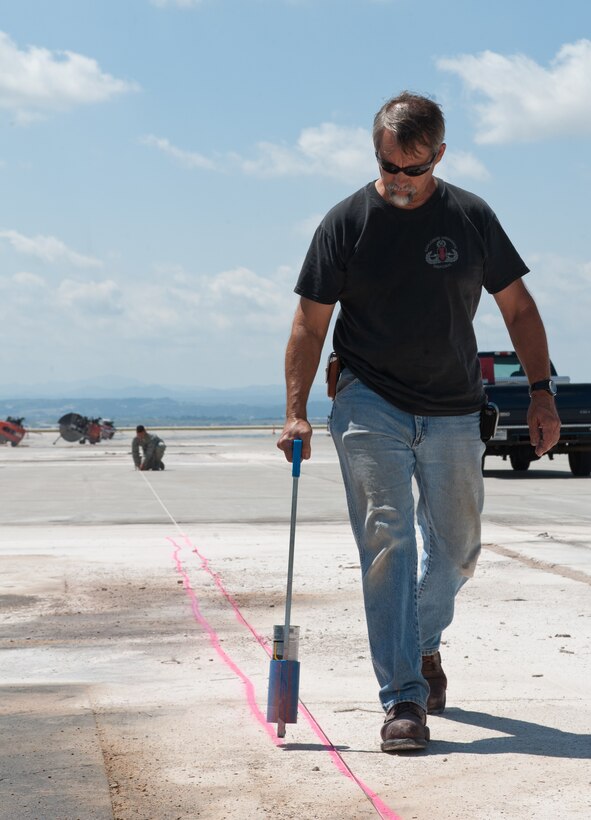 Craig Fairey, 28th Civil Engineer Squadron fuel distribution mechanic, marks an aircraft parking spot prior to deconstruction at Ellsworth Air Force Base, S.D., Aug. 5, 2013. These lines show the construction teams the location of underground utility lines to prevent damage during the renovation of aircraft parking spots. (U.S. Air Force photo by Airman 1st Class Alystria Maurer/Released)