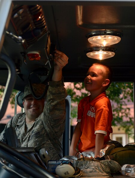 Airman 1st Class Lowell Boozer, 2nd Civil Engineer Squadron firefighter apprentice, shows the son of Staff Sgt. Curtis Sutton, from the 2nd Logistics Readiness Squadron, the inside of a fire truck during National Night Out on Barksdale Air Force Base, La., Aug. 6, 2013. Participants were given the opportunity to sit in the fire truck, honk the horn and blast the sirens. (U.S. Air Force photo/Senior Airman Micaiah Anthony)
