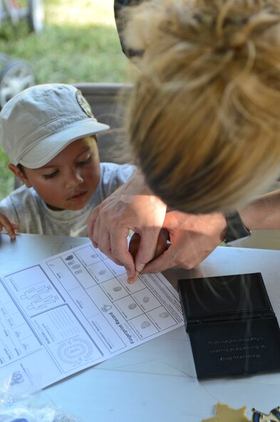 The son of Senior Airman Antonio Gonzalez, 2nd Bomb Wing Public Affairs videographer, makes a fingerprint for a child identification kit during National Night Out on Barksdale Air Force Base, La., Aug. 6, 2013. Child identification kits are used to help identify lost or missing children. Once the kit is completed, parents are instructed to keep them in a safe place. (U.S. Air Force photo/Senior Airman Micaiah Anthony)