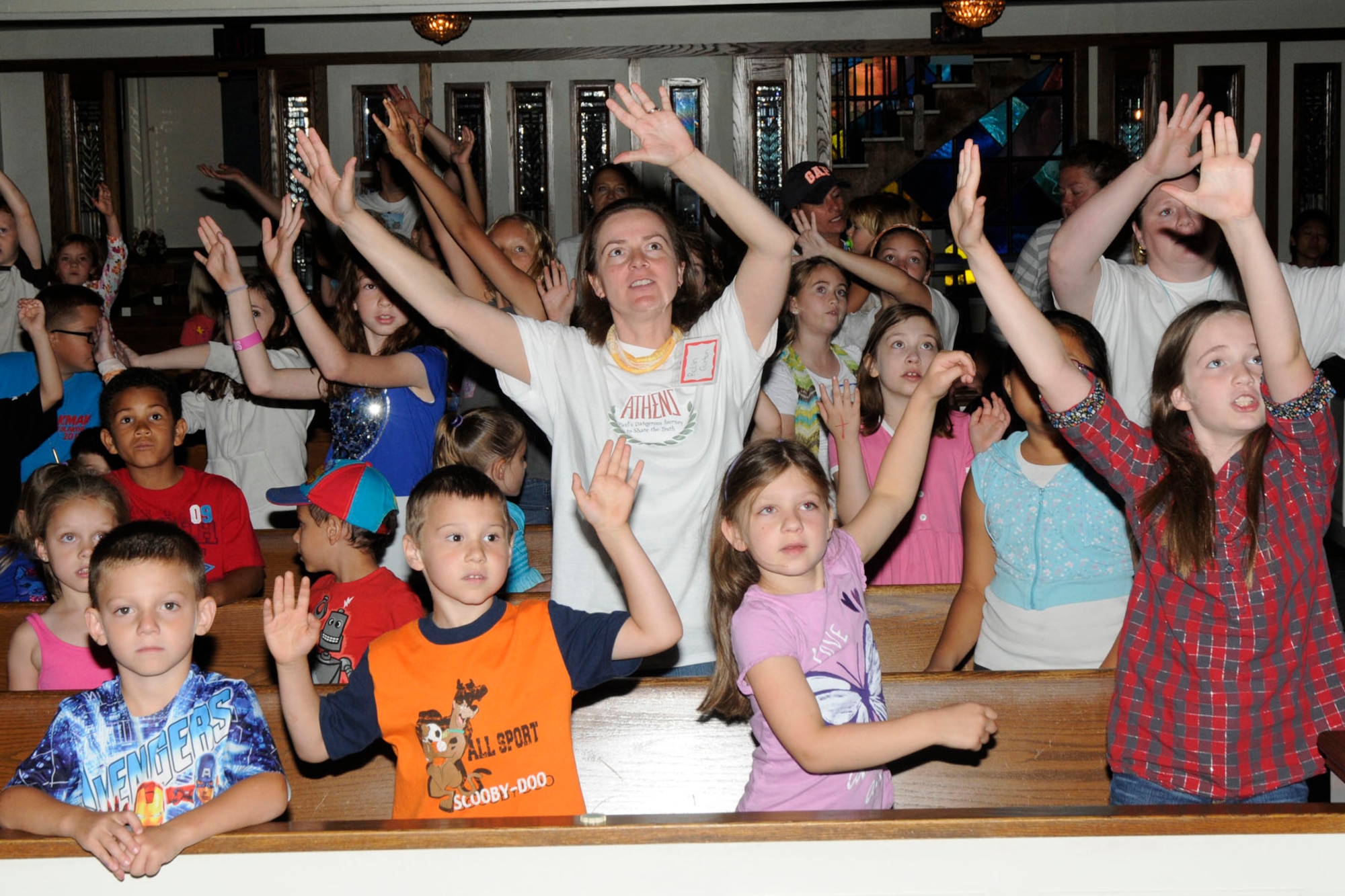 HANSCOM AIR FORCE BASE, Mass. – Children and volunteers raise their hands as they sing during Vacation Bible School at the base chapel Aug. 7. VBS is a program for kids ages five through fifth grade that integrates Bible lessons with fun activities and takes place for a week each summer. (U.S. Air Force photo by Linda LaBonte Britt)