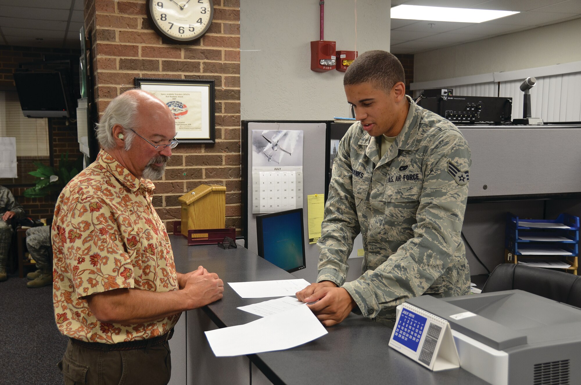 WRIGHT-PATTERSON AIR FORCE BASE, Ohio - Senior Airman Harvey Eubanks, 87th Aerial Port Squadron air transportation journeyman, helps a customer while working the customer service desk during the July 13 unit training assembly at the Wright-Patterson Base Operations and Passenger Terminal. Five 87 APS Airmen worked at the terminal on the July 13-14 and 27-28 UTAs to process passengers, provide security checks and handle baggage. The Airmen are trained to process passengers flying on any type aircraft from any branch of the military. They can also work with non-military planes that have passengers. (U.S. Air Force photo/Master Sgt. Charlie Miller)