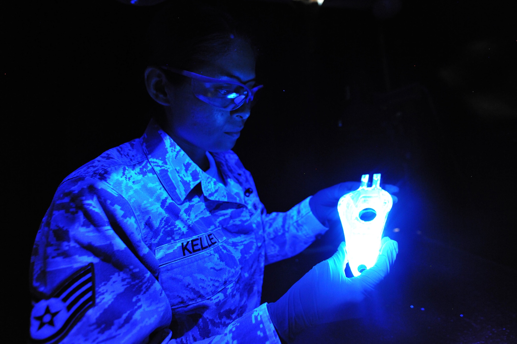 Staff Sgt. Bernadett Kelley, 86th Maintenance Squadron nondestructive inspection technician, views a part underneath black light during the inspection step of the penetrant process, July 31, 2013, Ramstein Air Base, Germany.  Any penetrant that has seeped into cracks is now visible due to the penetrants natural fluorescence under black light. (U.S. Air Force photo/Senior Airman Chris Willis)