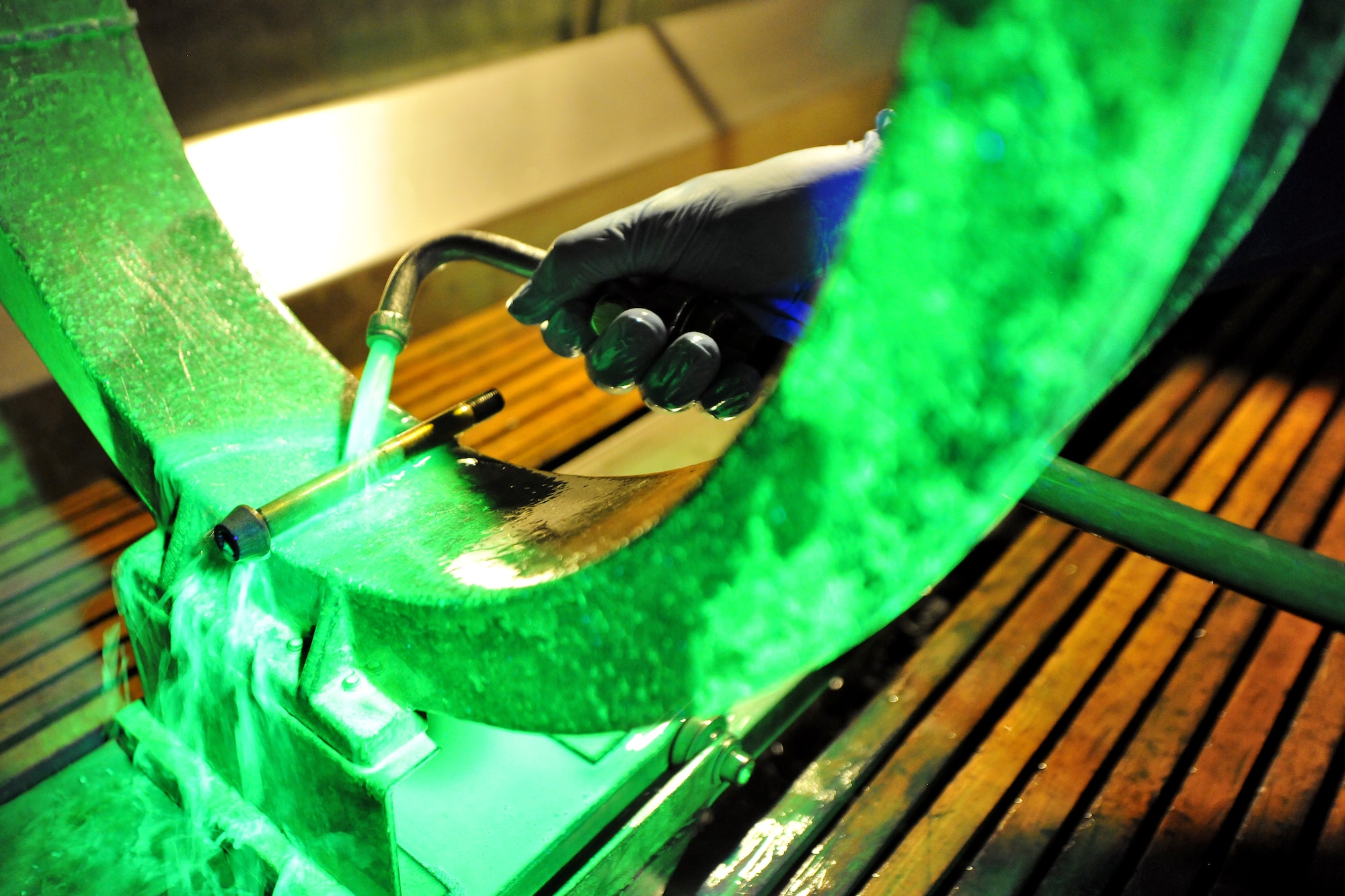 Fluorescent magnetic particle bath flows over a nose landing gear wheel bolt during an inspection, July 31, 2013, Ramstein Air Base, Germany.  The fluorescent color comes from suspended iron particles which glow while under a black light.  These iron particles are attracted to leakage fields caused by cracks in ferrous materials after being magnetized.  (U.S. Air Force photo/Senior Airman Chris Willis)