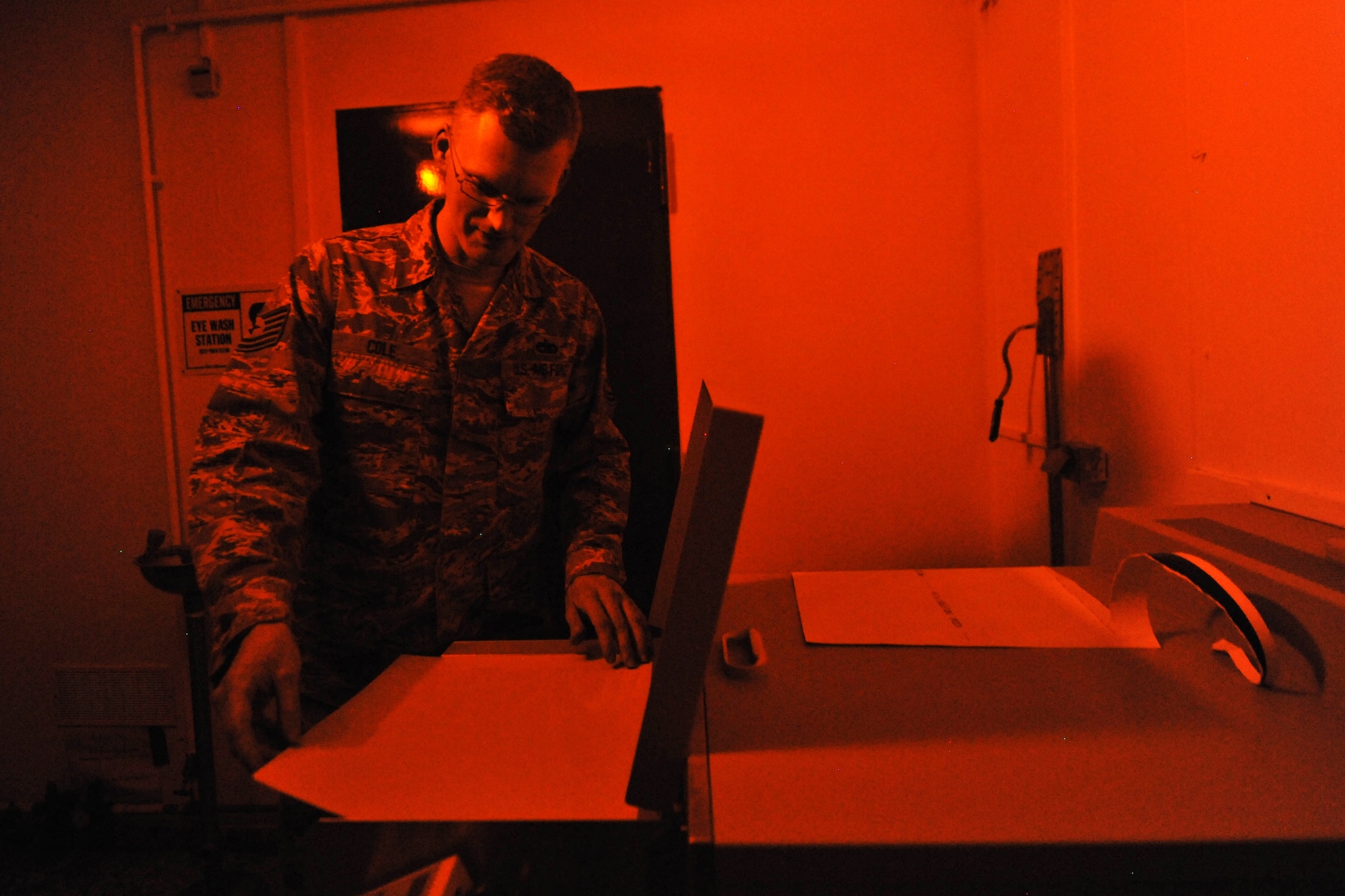 Tech. Sgt. Jeremy Cole, 86th Maintenance Squadron nondestructive inspection technician, loads radiographic film into an automatic film processor under the cover of safelight, July 31, 2013, Ramstein Air Base, Germany.  The film processor automatically develops, fixes, washes and dry’s the film, making it ready for viewing. (U.S. Air Force photo/Senior Airman Chris Willis)