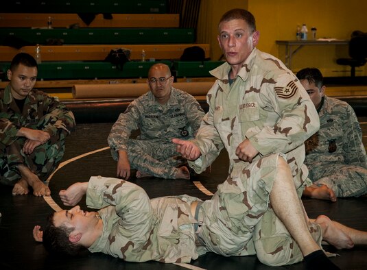 U.S. Air Force Staff Sgt. Christian Coleman, Misawa Combatives instructor, shows members of the Misawa Combatives class how to go from full-guard to half-guard at Misawa Air Base, Japan, July 30, 2013. Coleman is certified in Level 2 Modern Army Combatives and leads the Misawa Combatives Program. (U.S. Air Force photo by Airman 1st Class Zachary Kee)