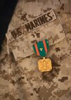 A Navy and Marine Corps Achievement Medal with Combat Distinguishing Device hangs from the chest of Cpl. Ryan T. McSweeney, a Middletown, Ohio, native and recovery vehicle operator with Transportation Support Company, Combat Logistics Regiment 2, Regional Command (Southwest), after an awards ceremony at Camp Leatherneck, Afghanistan, July 23, 2013. McSweeney helped reorganize the defense of a forward operating base after personally neutralizing two attacking insurgents May 13, 2013.