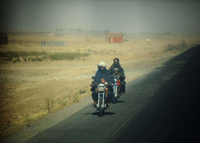 Two Afghan motorists approach the rear of convoy during a resupply mission conducted by Transportation Support Company, Combat Logistics Regiment 2, Regional Command (Southwest), in Helmand province, Afghanistan, July 25, 2013. Marine convoys operating in Helmand share the road with a wide assortment of civilian vehicles that intermingle with the military caravans.