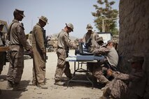 Marines line up to purchase items from Sgt. Arthur Doers, a native of Iron Mountain, Mich., and Marine Corps Community Services Marine with Combat Logistics Regiment 2, Regional Command (Southwest), at a forward operating base in Helmand province, Afghanistan, Aug. 4, 2013. Doers provided access to a mobile Post Exchange, which sold various hygiene, uniform and food commodities rarely seen by servicemembers operating at the isolated base. 