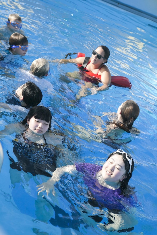 Ayano Murakami, left, and Miki Sugawara swim with Marine families Aug. 4 at the 50-meter pool on Camp Foster during the luau pool party. The party was part of the 3rd annual Oshima youth cultural exchange program. The exchange program was established as part of the Marine Corps Community Services Okinawa Child, Youth and Teen program to promote the needs of American children and the children of Oshima. The participants are students between the ages of 13 and 18. Photo by Lance Cpl. Natalie M. Rostran
