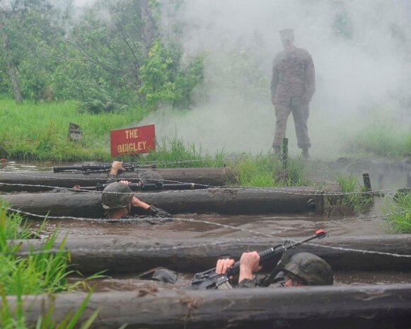 Under the watchful eye of an Officer Candidates School staff member, Officer candidates from Echo Company negotiate The Quigley, one of the obstacles making up the Combat Course, at OCS on June 7, 2013. The Quigley is an obstacle that includes maneuvering cement culverts, logs and barbed wire.