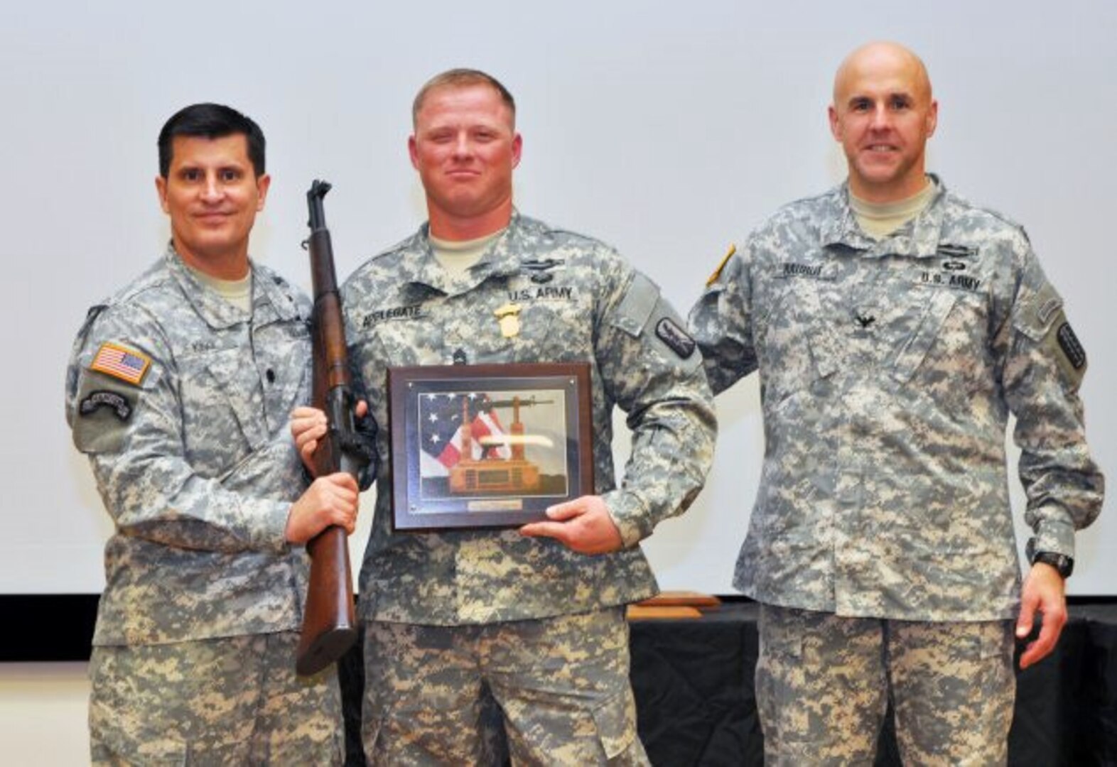 Sgt. 1st Class Geoffrey Applegate, center is presented a Secretary of the Army M-1 Garand Trophy Rifle by Lt. Col. Don King, commander, U.S. Army Marksmanship Unit, and Col. Michael W. Rauhut, commander, 197th Infantry Brigade.