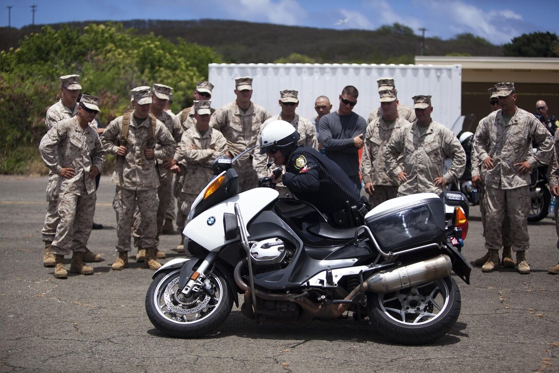 A motorcycle police officer with Honolulu Police Department, shows Marines from 2nd Battalion, 3rd Marine Regiment’s Motorcycle Mentor Program how to pick up a fallen motorcycle after discussing the importance of motorcycle safety at the Marine Corps Base Hawaii airfield, Aug. 2, 2013. (U.S. Marine Corps photo by Lance Cpl. Suzanna Knotts)
