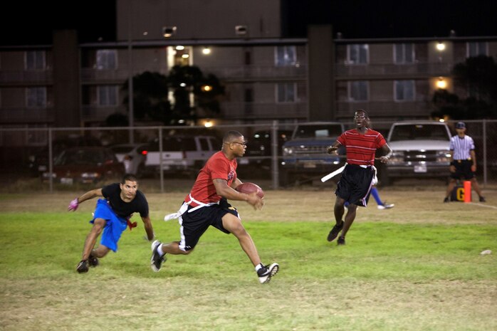 Maleek Ferguson (center), corner and safety for Installation Personnel Administration Center, runs the ball during the 101 Days of Summer Flag Football Tournament championship game against Patrol Squadron 4 at Pollock Field, Aug. 5, 2013. (U.S. Marine Corps photo by Lance Cpl. Suzanna Knotts)