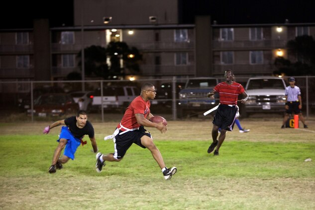 Maleek Ferguson (center), corner and safety for Installation Personnel Administration Center, runs the ball during the 101 Days of Summer Flag Football Tournament championship game against Patrol Squadron 4 at Pollock Field, Aug. 5, 2013. (U.S. Marine Corps photo by Lance Cpl. Suzanna Knotts)
