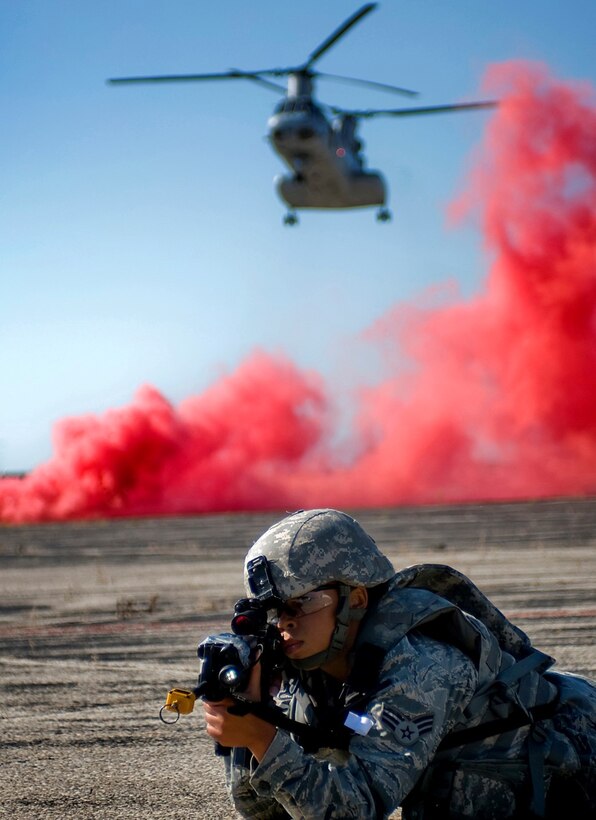 Senior Airman Krystal Collier secures a landing zone for a Marine CH-46 Sea Knight as the helicopter lands in the background during a joint, mass-casualty exercise Aug. 4, 2013, at Grissom Air Reserve Base, Ind. Collier and other Airmen assigned to the 434th Security Forces Squadron embedded with Marines and Air Force explosive ordinance disposal units during an initial assault to secure a voting location in a simulated overseas nation. Collier is a fire team member assigned to the 434th SFS. (U.S. Air Force photo/Tech. Sgt. Mark R. W. Orders-Woempner) 