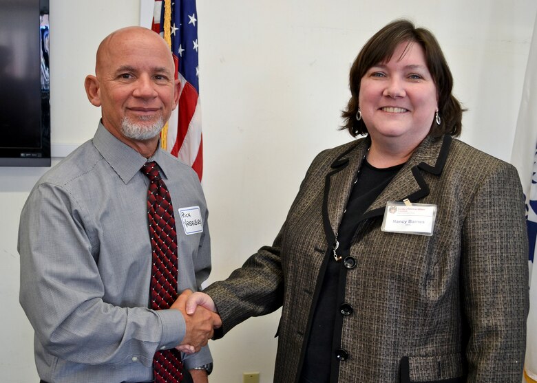 Rick Vrendenburg, USACE San Francisco District’s Small Business Deputy receives a coin from Nancy Barnes, Society of American Military Engineers (SAME) – San Francisco Post’s program organizer at Coast Guard Island, Calif., Aug. 8, 2013. Vrendenburg, keynote speaker at the monthly event, advocated small businesses to inform the Corps about their classifications such as “Woman Owned” or “Disabled Veteran Owned” as a way to open the door for future opportunities.