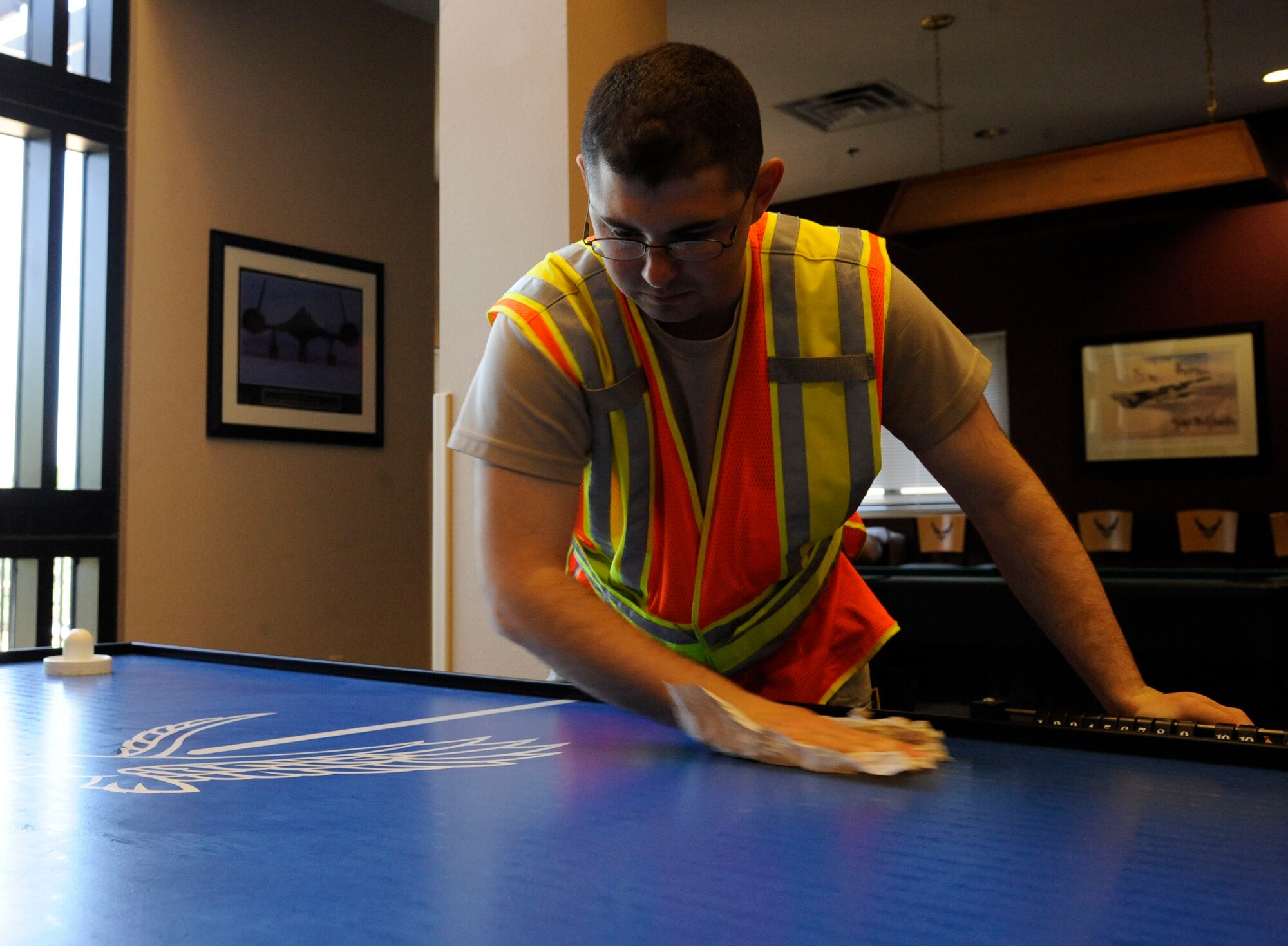 Airman John Brooks II, 2nd Security Forces Squadron patrolman, cleans an air hockey table during bay orderly duty on Barksdale Air Force Base, La., Aug. 9, 2013. An orderly's duties include maintaining the grounds of the dormitories, escorting contracted workers and reporting any damages found in the dormitory facilities. (U.S. Air Force photo/Airman 1st Class Andrew Moua)