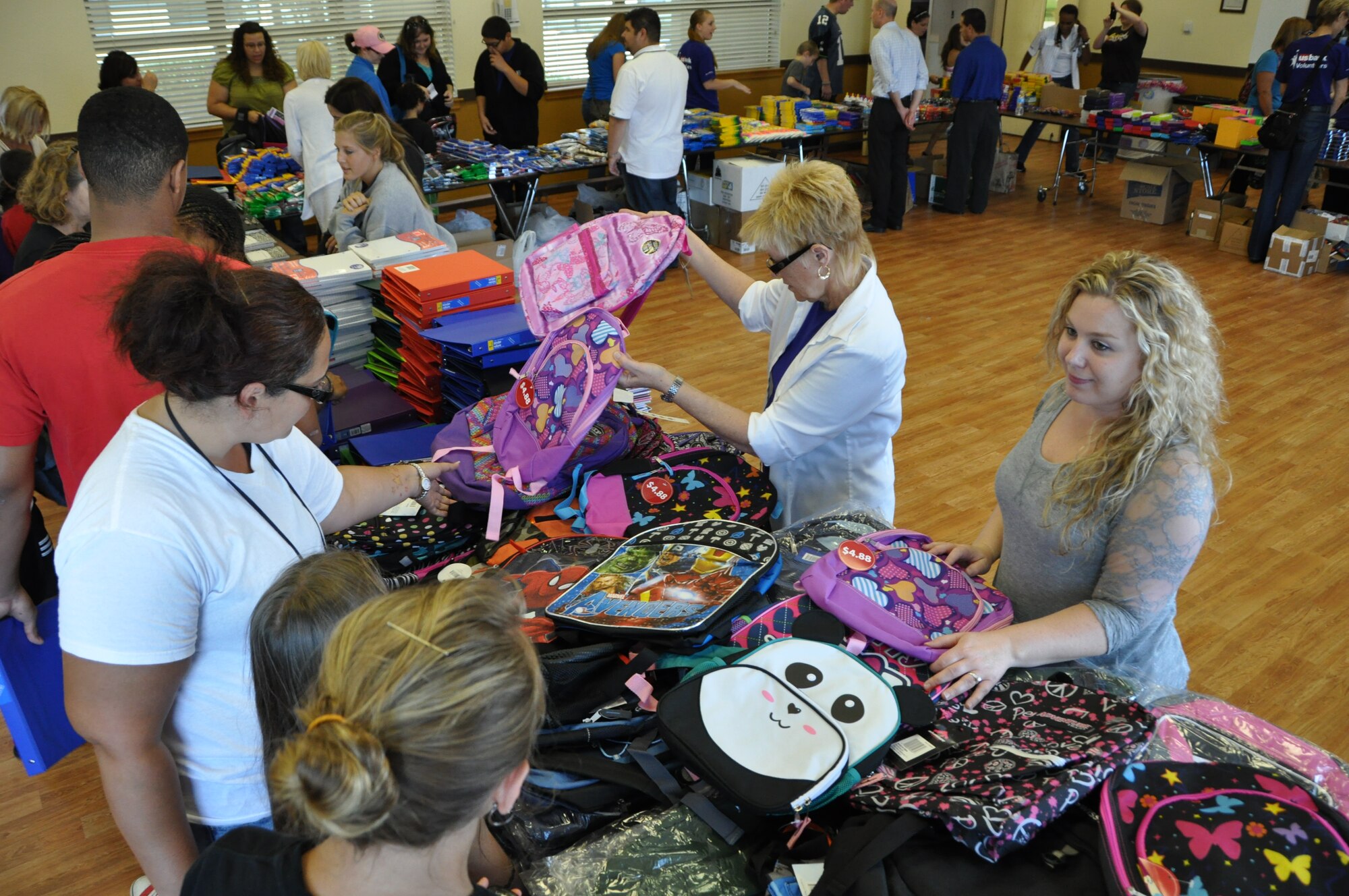 Volunteers from U.S. Bank hand out backpacks to be filled with supplies
to Travis youths yesterday at the First Street Chapel on Traivs. (U.S. photo/Staff Sgt. Patrick Harrower)