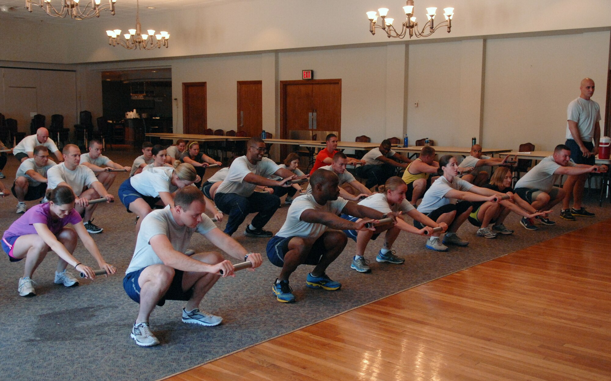 U.S. Air Force Airmen are instructed on how to properly perform a squat during a running seminar Aug. 7, 2013, at the Dyess Event Center on Dyess Air Force Base, Texas.  The seminar was conducted by U.S. Air Force Lt. Col. Antonio Eppolito, Air Force Medical Support Agency, who provided members with information on aerobic development, running form, injury prevention and how to improve performance. He educated servicemembers on the barefoot style running, which is more efficient for the body by limiting pain and injuries. This can be accomplished by wearing a minimalist running shoe. According to Eppolito, wearing thick-heeled tennis shoes force people to land on their heels, which causes more injuries and shortens the achilles tendon by limiting flexibility in the foot. Eppolito has been a member of the Air Force running team for 18 years and is a five-time Air Force Masters Half-Marathon champion. (U.S. Air Force photo by Senior Airman Shannon Hall/Released)