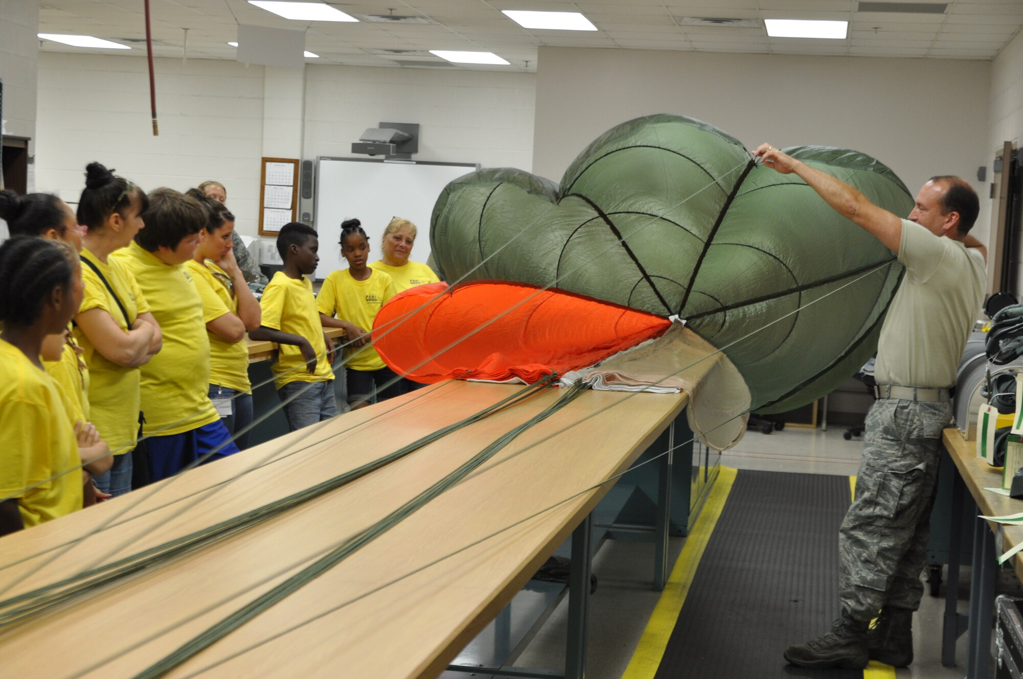 YOUNGSTOWN AIR RESERVE STATION, Ohio – Air Force Reserve Tech. Sgt. Rob Runnion, an Aircrew Flight Equipment technician assigned to the 910th Operations Support Squadron, demonstrates a parachute during a tour by the Children’s Opportunities for Outside Learning program from Farrell, Pa. here, July 19, 2013. YARS accepts reservations for groups of 20-40 people for tours of the installation on selected Fridays during the tour season. For additional information about the YARS tour program, please contact the 910th Airlift Wing Public Affairs Office at 330-609-136. U.S. Air Force photo by Master Sgt. Bob Barko Jr.