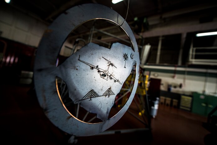 A sheet metal sign with a C-17 Globemaster III, the Arthur Ravenel Jr. Bridge and a Palmetto tree with a crescent, hangs in the 437th Maintenance Squadron aircraft metals shop Aug. 7, 2013, at Joint Base Charleston, S.C. Airmen from the aircraft metals fabrication shop are trained to use several different pieces of equipment to bend, cut and combine metals. (U.S. Air Force photo/Senior Airman Dennis Sloan)