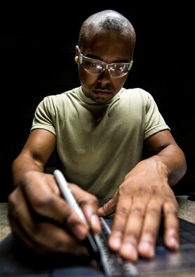 Airman 1st Class William Williams, 437th Maintenance Squadron aircraft metals technology journeyman, lays out a cut with a ruler and black marker on a sheet of metal Aug. 7, 2013, at Joint Base Charleston, S.C. The sheet metal is used to simulate steel work on a C-17 Globemaster III wing. (U.S. Air Force photo/Senior Airman Dennis Sloan) 

