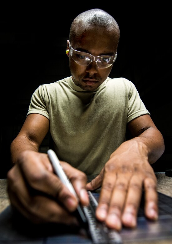 Airman 1st Class William Williams, 437th Maintenance Squadron aircraft metals technology journeyman, lays out a cut with a ruler and black marker on a sheet of metal Aug. 7, 2013, at Joint Base Charleston, S.C. The sheet metal is used to simulate steel work on a C-17 Globemaster III wing. (U.S. Air Force photo/Airman 1st Class Dennis Sloan)